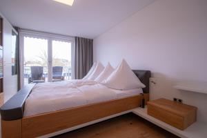 a bedroom with a bed with white sheets and a window at Traumwohnung in Norderney