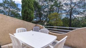 a white table and chairs on a balcony with trees at Lisa Maria D N38 2P5 in Sari Solenzara