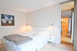 a white bedroom with a bed and a mirror at Ferienwohnung Meeresrauschen in Norderney