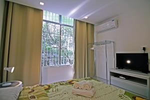 1 dormitorio con 1 cama, ventana y TV en Rio Spot Homes Copacabana U033, en Río de Janeiro