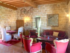 een woonkamer met rode stoelen en een stenen muur bij Le Castillou in Luc-sur-Aude