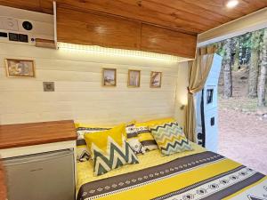 a bed in a tiny house with yellow pillows at Tenerife Stylish Camper Van with Bathroom in Arona