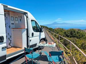a white van with chairs and a table on a balcony at Tenerife Stylish Camper Van with Bathroom in Arona