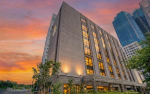 een hoog gebouw met een zonsondergang op de achtergrond bij Haeundae The Van Hotel in Busan