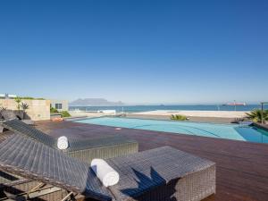 uitzicht op een zwembad en de oceaan bij Infinity Self Catering Apartments in Bloubergstrand