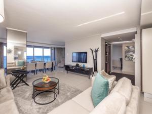 een woonkamer met een bank en een tafel bij Infinity Self Catering Apartments in Bloubergstrand