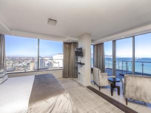 een slaapkamer met een groot bed en grote ramen bij Infinity Self Catering Apartments in Bloubergstrand +13 foto's