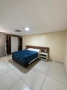 a bedroom with a bed with a blue comforter at Imperial Flat orla de tambáu in João Pessoa +5 photos