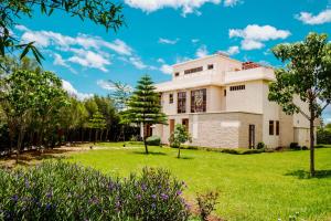 een huis op een groen gazon met paarse bloemen bij Maiyan Nanyuki in Nanyuki