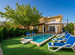 a backyard with a swimming pool with chairs and an umbrella at Ideal Property Mallorca - Villa Feel Good in Alcudia