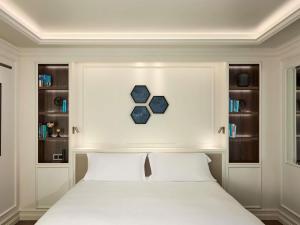 una camera da letto con un letto bianco con due cuscini di Sofitel Barcelona Skipper a Barcellona Altre 149 foto