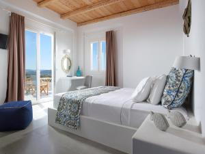 een witte slaapkamer met een bed en een balkon bij Lithos Luxury Rooms (Adults Only) in Adamas