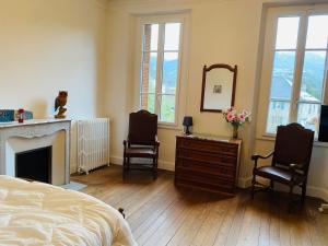 een slaapkamer met een bed, 2 stoelen en een spiegel bij La Villa Madeleine in Jausiers