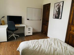 een slaapkamer met een bed en een bureau met een computer bij La Villa Madeleine in Jausiers