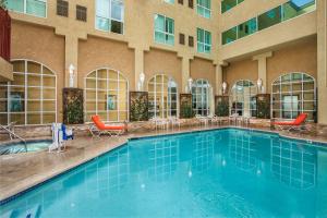 a swimming pool in a hotel with chairs and a building at Desert Palms Hotel & Suites Anaheim Resort in Anaheim