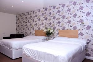 two beds in a room with flowers on the wall at Ashiana in Newark-on-Trent