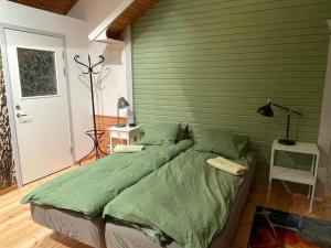 Bett in einem Zimmer mit grüner Wand in der Unterkunft Litet hus utanför Luleå in Luleå