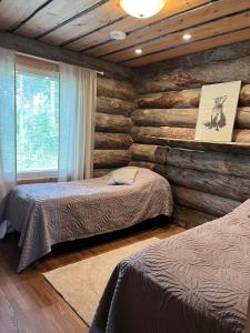 1 Schlafzimmer mit 2 Betten und einer Holzwand in der Unterkunft Napapiirin Järvilomat in Rovaniemi