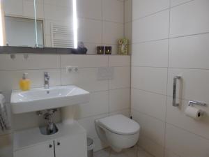 a white bathroom with a sink and a toilet at Ferienwohnung Am Kräutergarten - mit Pool, Sauna und Garage in Missen-Wilhams +30 photos