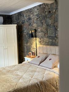 a bedroom with a bed with a stone wall at Aprosmeno House 6 in Agros