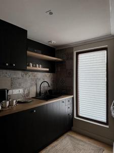 a kitchen with black cabinets and a window with a sink at Aprosmeno House 6 in Agros