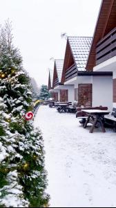 a snow covered yard with benches and a building at Solina domki-„Solińskie wzgórze” in Solina