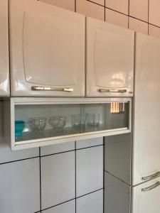 a kitchen with white cabinets and glass bowls on a shelf at 1 Quarto passos da praia in Fortaleza