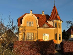 ein großes gelbes Haus mit rotem Dach in der Unterkunft Lyst og rummeligt kælderværelse in Brabrand
