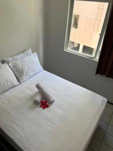 a white bed with a red flower on it at 1 Quarto passos da praia in Fortaleza