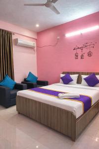 a bedroom with a large bed and a pink wall at Hotel Golden Suites in Bangalore