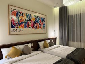 two beds in a hotel room with a painting on the wall at GAJOs HOUSE in Thanh Xuân