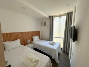 a hotel room with two beds and a window at Vila em Laranjeiras in Rio de Janeiro