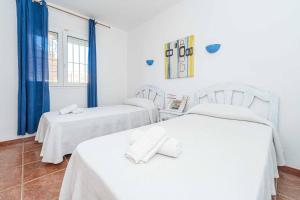 2 letti bianchi in una camera con tende blu di Villa Nispero a El Tosalet Altre 17 foto