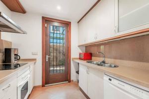 a kitchen with white cabinets and a sink and a door at Villa Oceana in Manilva