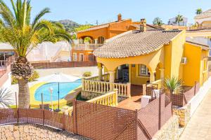 una casa gialla con piscina e recinzione di Villa Pera a El Tosalet