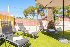 un gruppo di sedie e un ombrellone su un prato di Villa Pera a El Tosalet