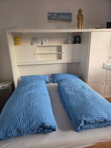 a bed with two blue pillows on it at Inselpause in Wittdün