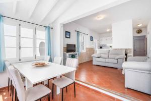 a dining room and living room with a white table and chairs at Villa Punta Rosa in Punta Prima