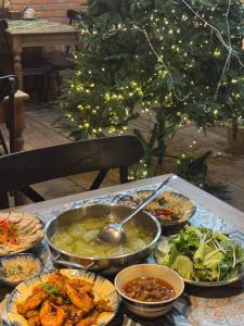 a table with bowls of food and a christmas tree at GAJOs HOUSE in Thanh Xuân