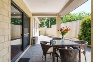 an outdoor patio with a glass table and chairs at Queens Residence Perth Western Australia in Perth