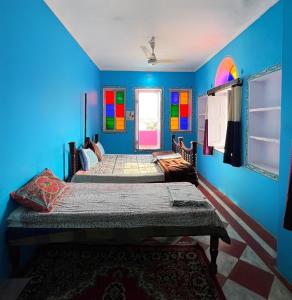 Twee bedden in een blauwe kamer met kleurrijke muren. bij Hotel Paramount Palace in Pushkar