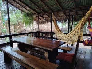 a porch with a hammock and a wooden table and benches at Recanto Shanti in Alter do Chao