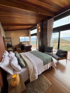 a bedroom with a large bed and a view of the mountains at Chalé Manacá in Sapucaí-Mirim