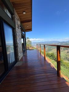 a wooden deck with a view of the mountains at Chalé Manacá in Sapucaí-Mirim