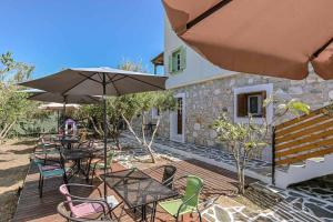 une terrasse en bois avec des tables, des chaises et un parasol dans l'établissement Naxos olive & home, à Engares