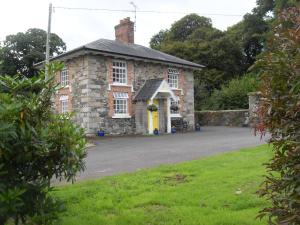 una vieja casa de piedra con una puerta amarilla en Cloverhill Gate Lodge, en Cloverhill