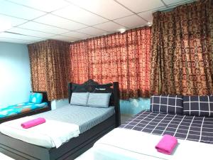 a bedroom with two beds and curtains with pink pillows at Capital O 91275 Pr Motel in Changlun