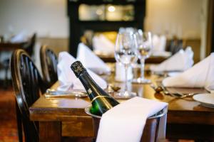 a wooden table with a bottle of champagne on it at Sun Inn in Pooley Bridge +30 photos