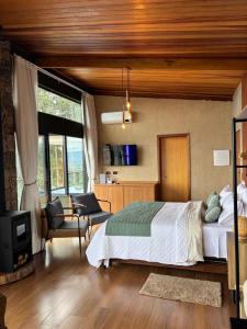a bedroom with a bed and a living room at Chalé Manacá in Sapucaí-Mirim +13 photos