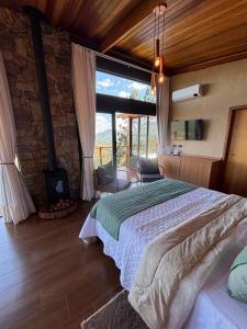 a bedroom with a large bed and a fireplace at Chalé Manacá in Sapucaí-Mirim